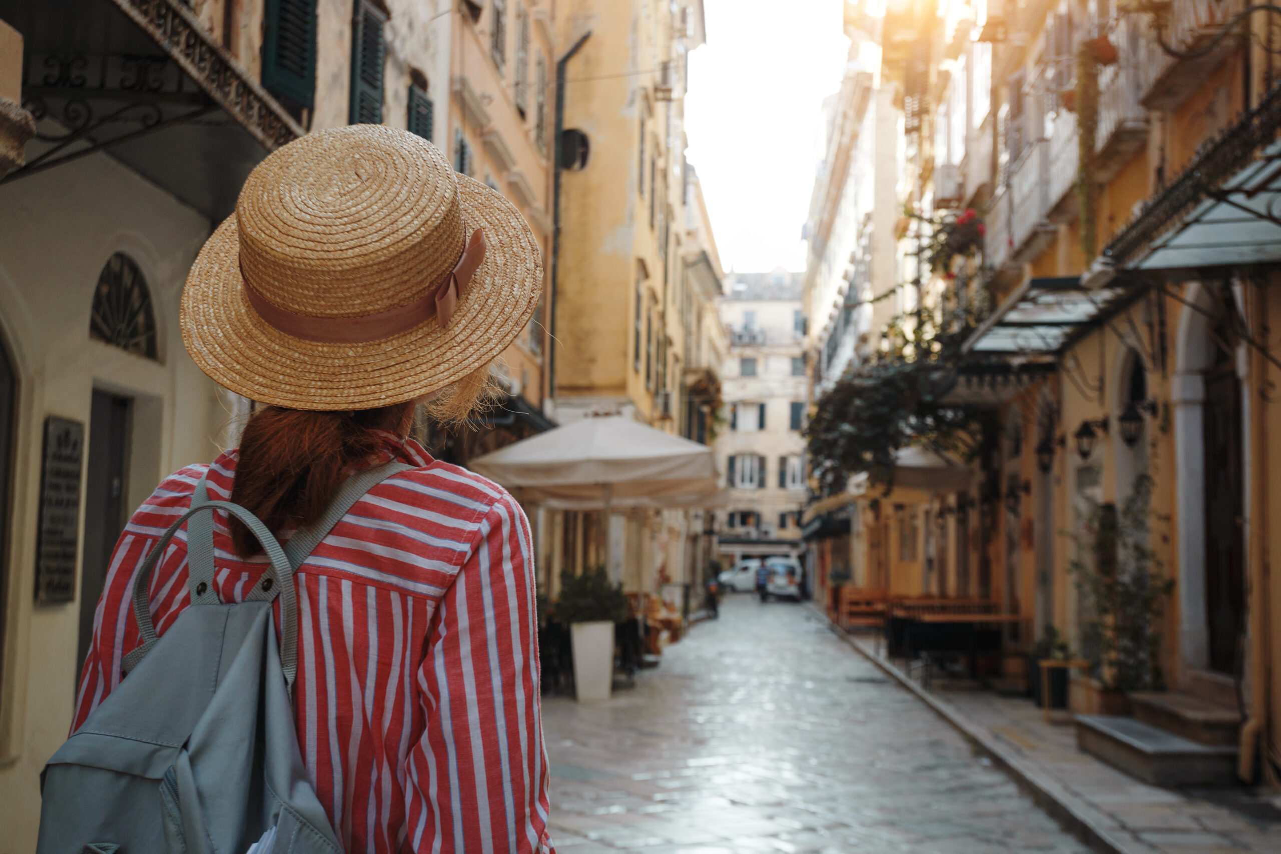 girl in a hat walks on the street of the ancient Greek city. Corfu Island in Greece,